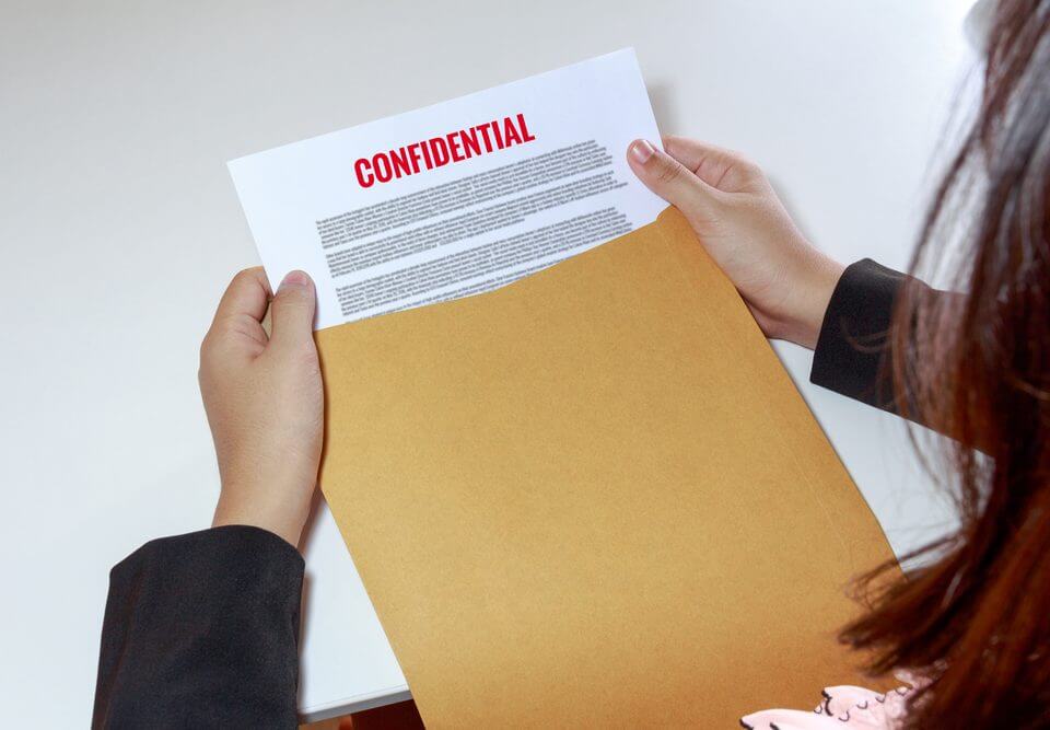 woman's hands holding a envelope with confidential paper