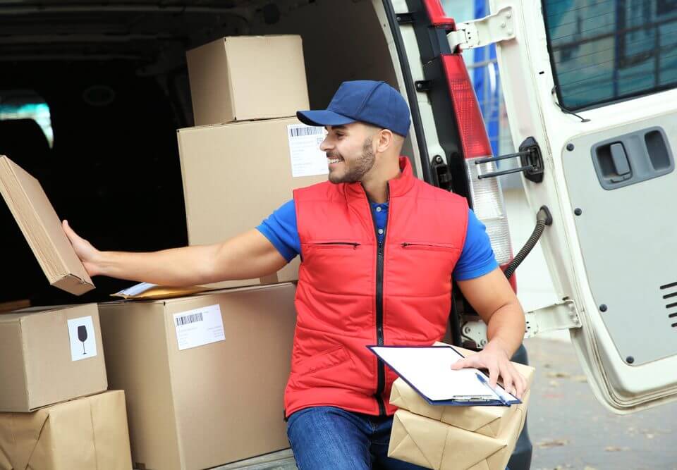 delivery driver wearing red vest in the back of delivery van with boxes in them