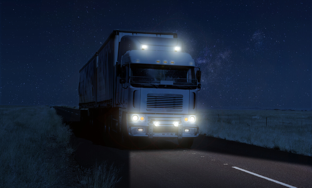 truck driving overnight in the dark to delivery goods and freight to its destination in a timely and safe manner