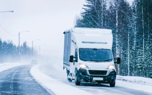 delivery truck van driving on a snowy road during the winter to safely drop off packages and mail to businesses and customers